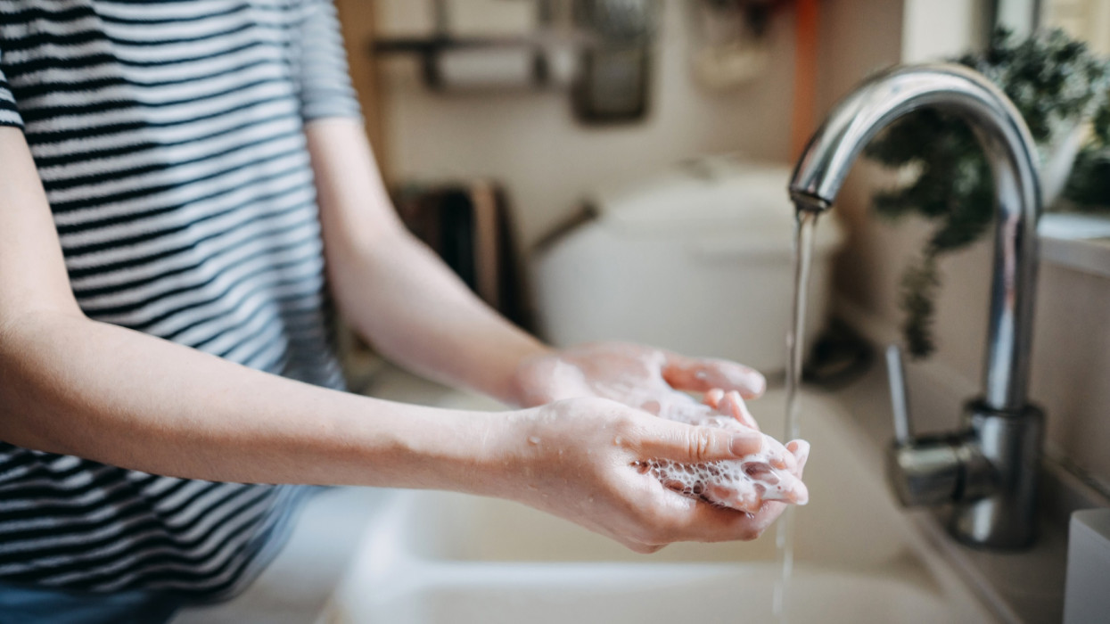 Cropped shot of a woman maintaining hands hygiene and washing hands with soap in the sink