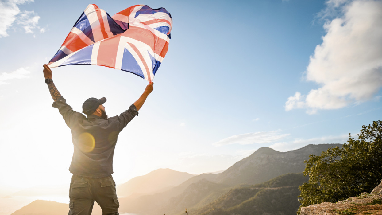 man with the English flag on the background of the sea and mountains