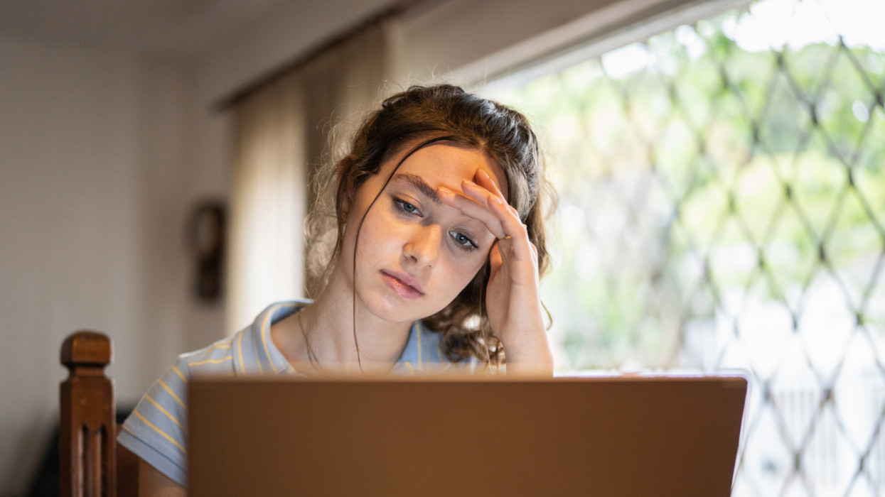 Tired or worried young woman using laptop at home student