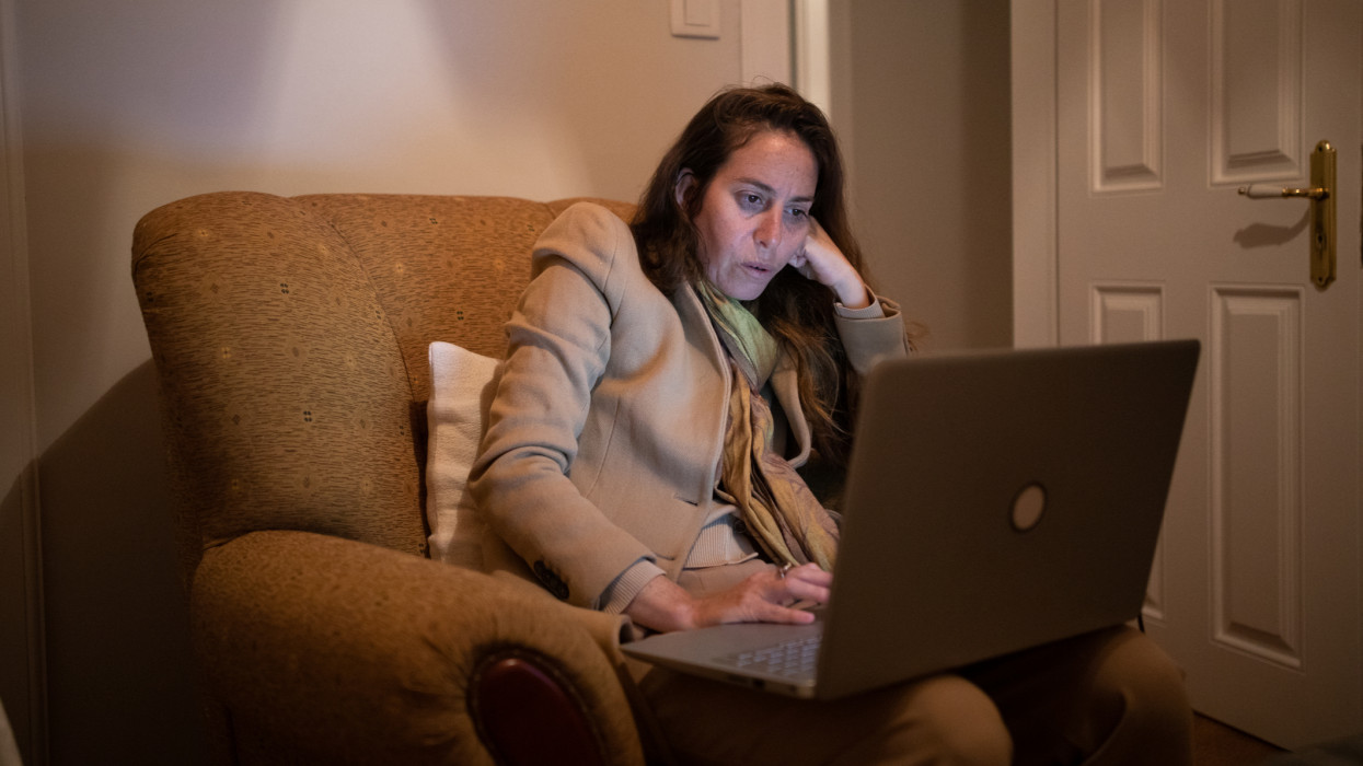 Woman works on laptop while sitting in armchair