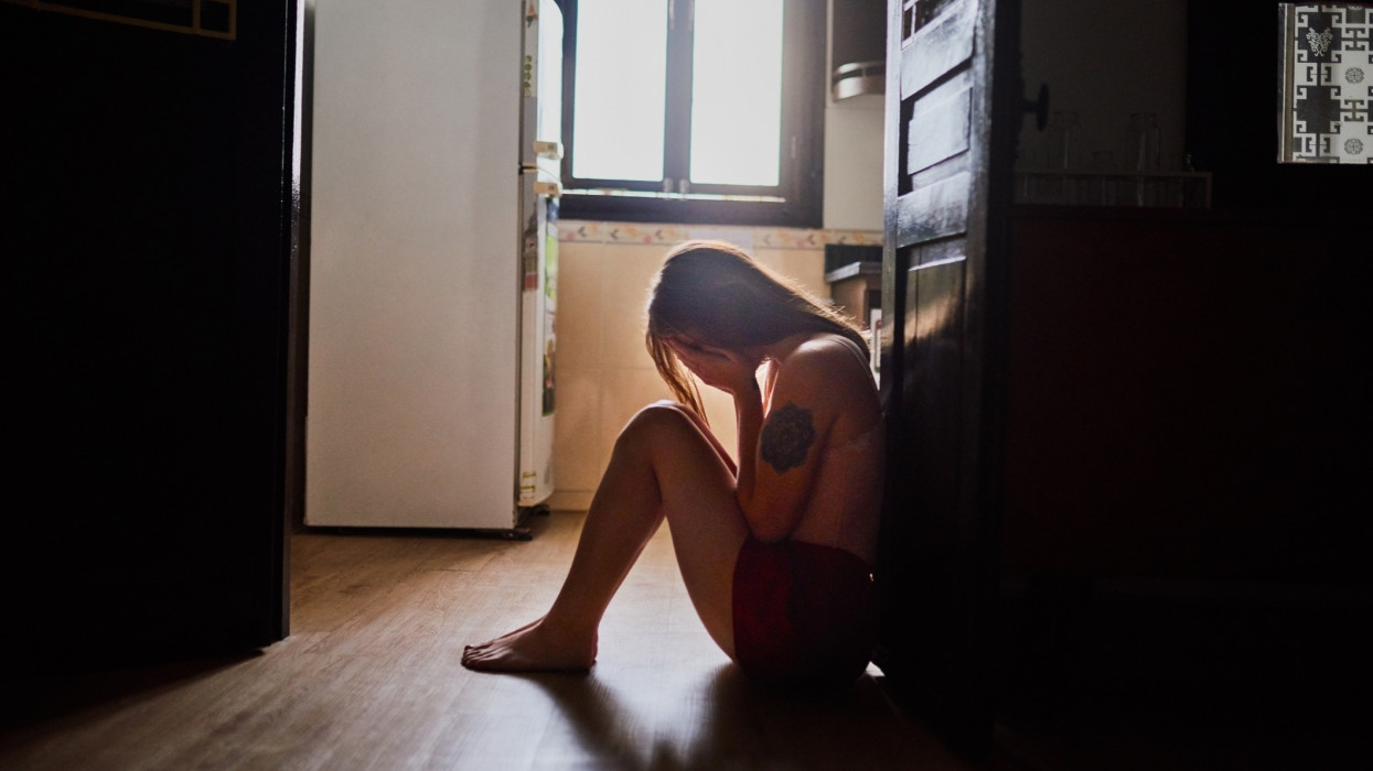 Full length shot of an attractive young woman sitting down and crying inside her apartment