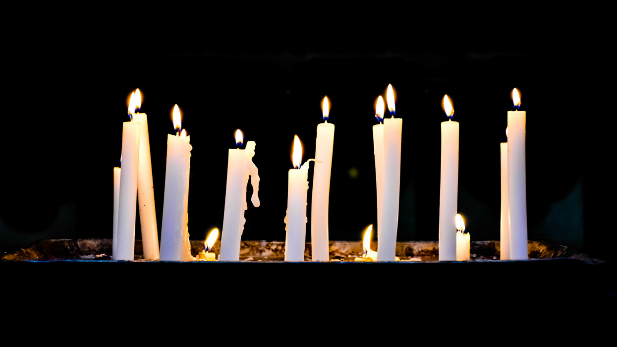 Several candlelights lit up in a row against black background
