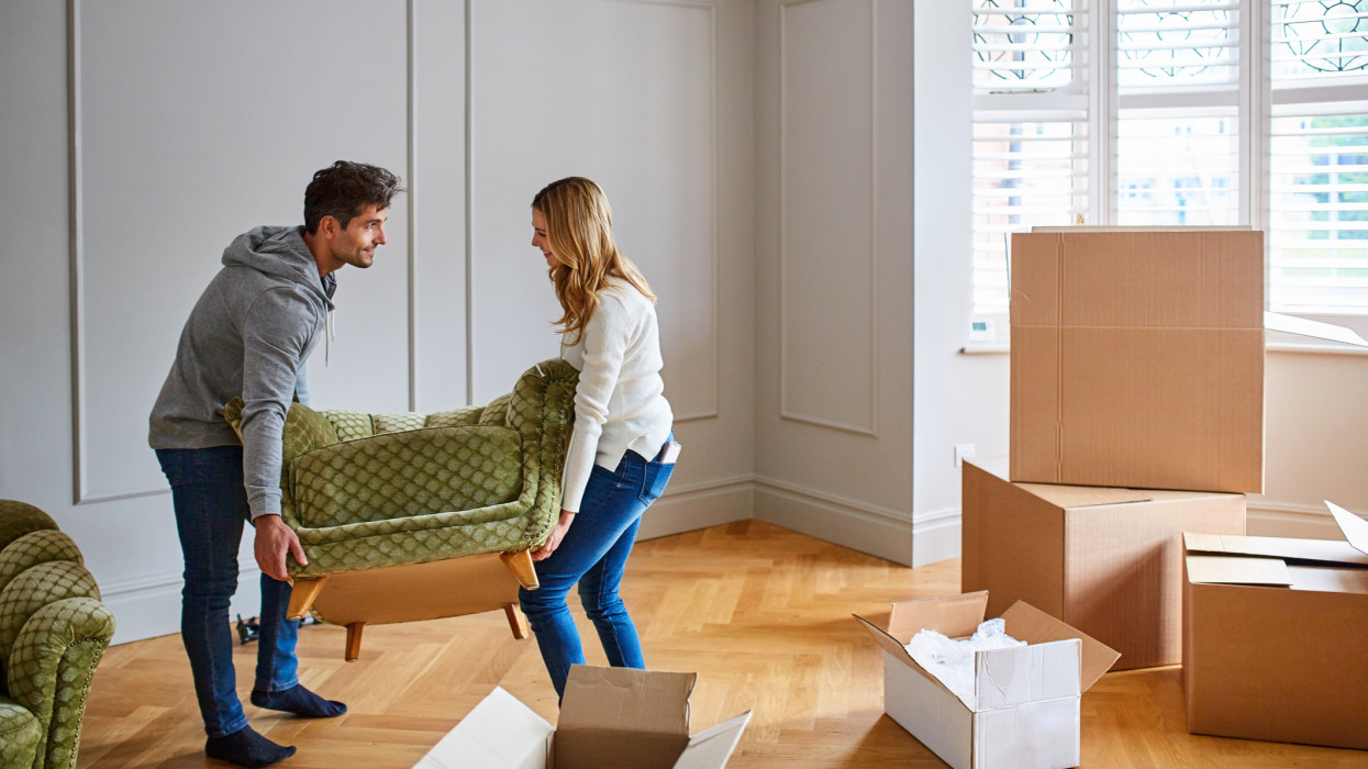Shot of a young couple moving a couch into their new home