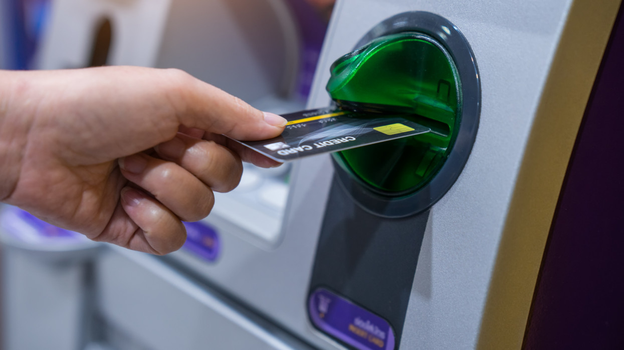 Woman hand is inserting card to atm machine to withdraw or transfer money