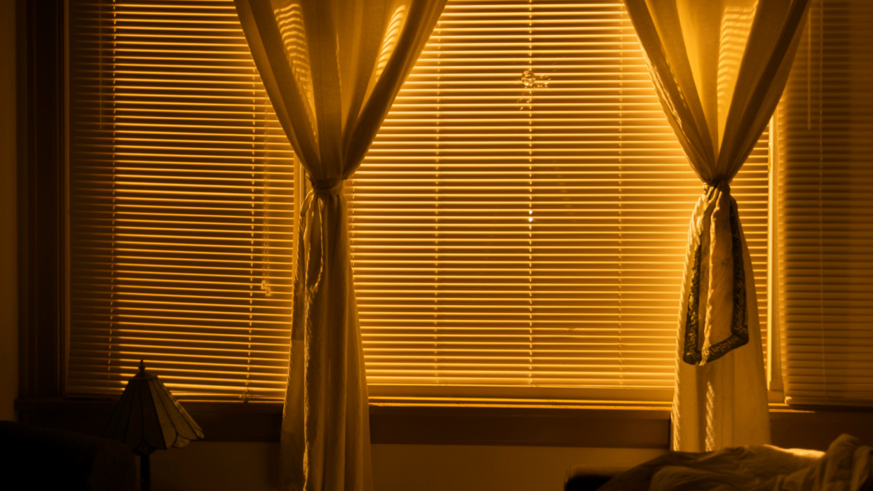 Curtains and blinds illuminated from street light at night.