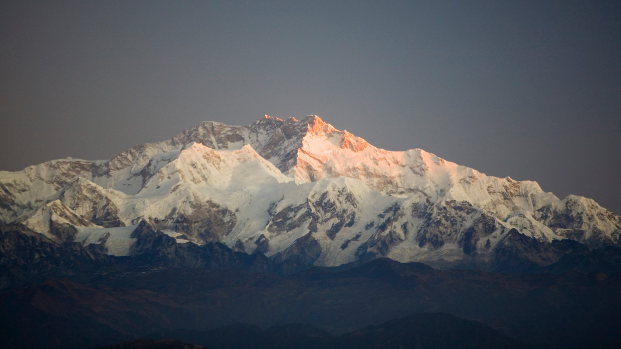 First sun rays hit summit of Kanchenjunga, worlds 3rd highest mountain, just East of Mt. Everest, squeezed between Nepal and Bhutan. Seen here from Phalut along Singalila Ridge trek.