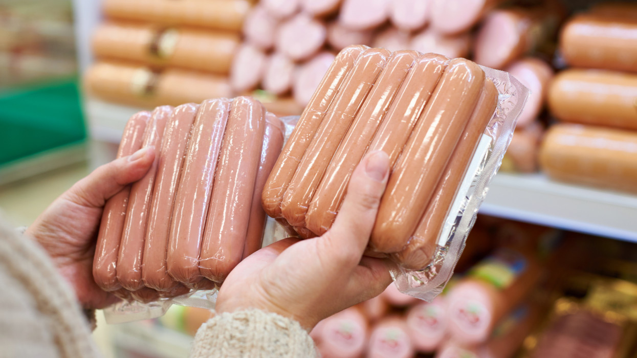 Woman chooses sausages in a vacuum package at the grocery store