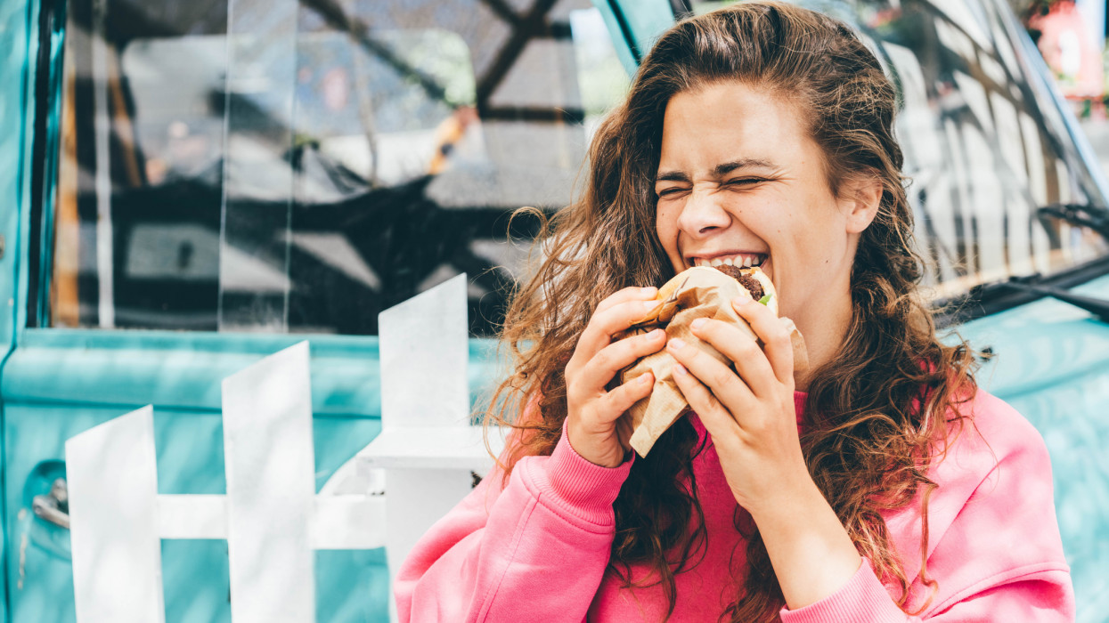 Smiling woman eating hamburger.