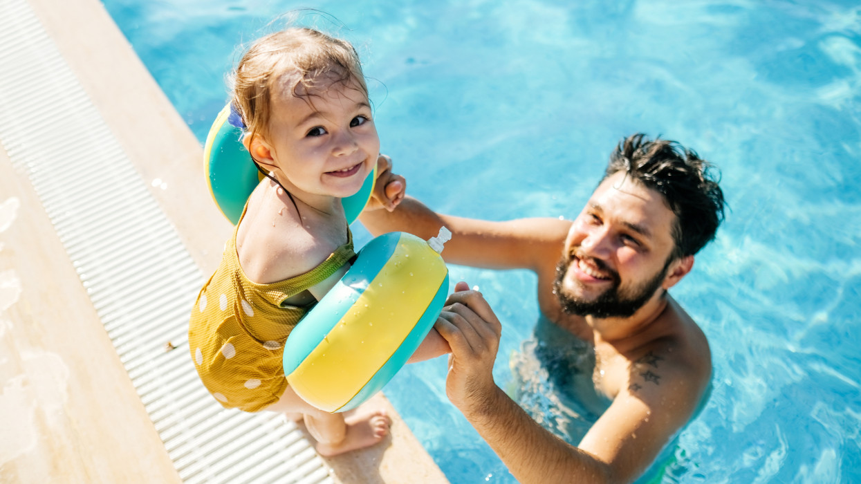 Cute little girl having fun with parents in pool kid summer vacation holiday bath father swimming