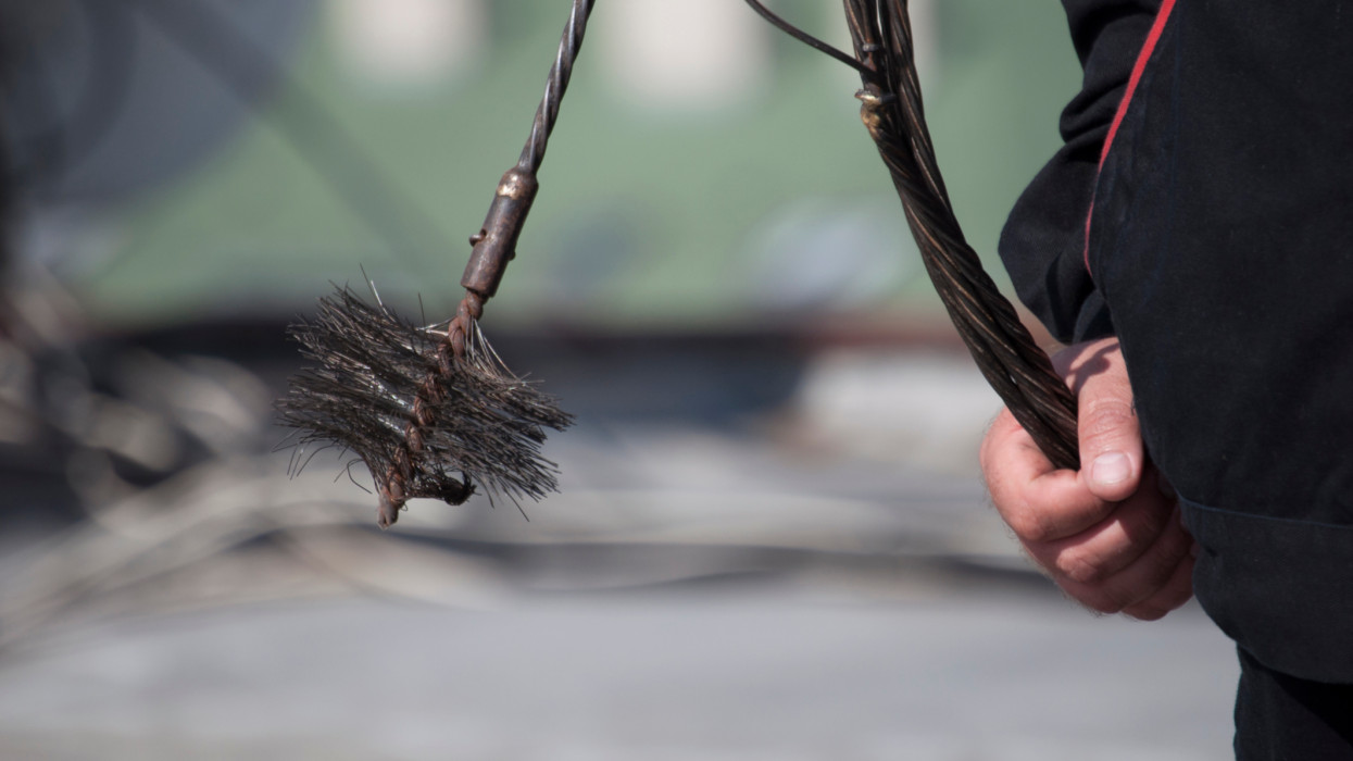 Chimney sweep at work, Close up of the hand holding a chain with the broom to clean the chimney
