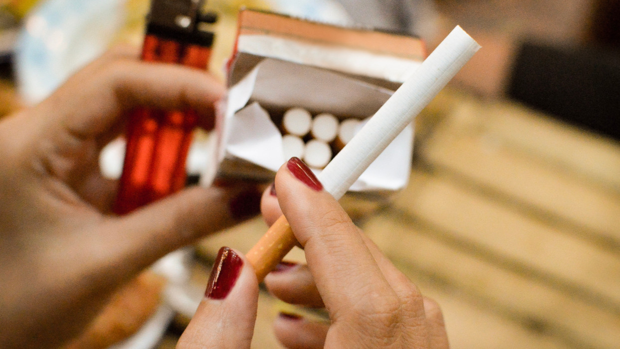Close up of a womans hands picking up cigarette from a box of cigarettes
