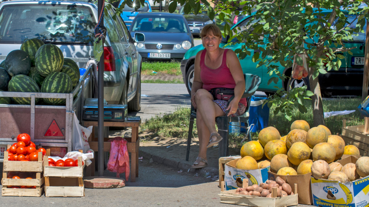 Zrenjanin, Serbia â July 29, 2020: A smiling saleswoman sitting under a shade and selling watermelons on the street in Zrenjanin, Serbia