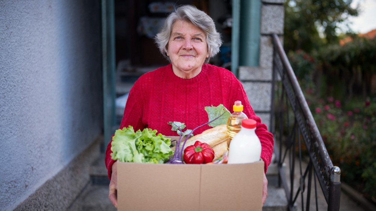 portrait of happy senior woman received crate with freshness food at home.