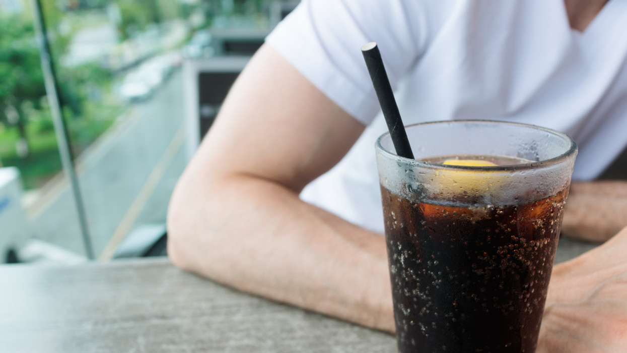 Close-up of unrecognizable white man at restaurant with beverage served with paper straw