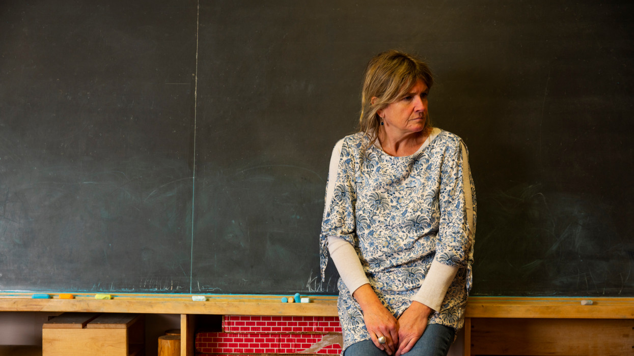 A stressed or depressed mature teacher in a classroom.