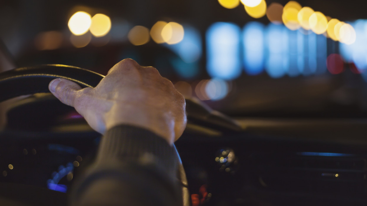 Close up of man hand on car steering wheel driving through a tunnel