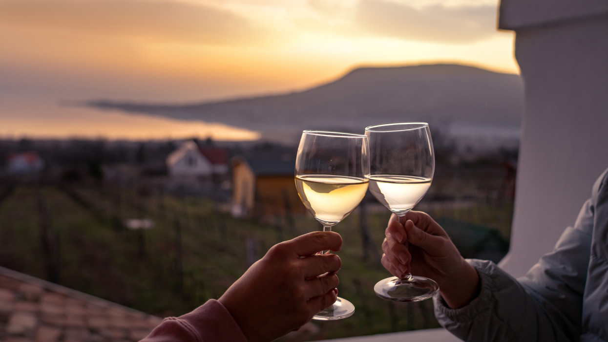 toast with wine glasses at lake Balaton with the Badacsony hill in the background .