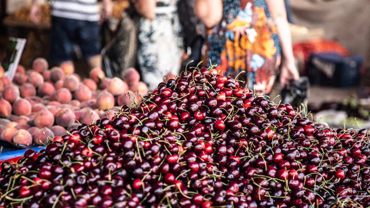 A large pile of cherries on the counter in the market ready for sale.