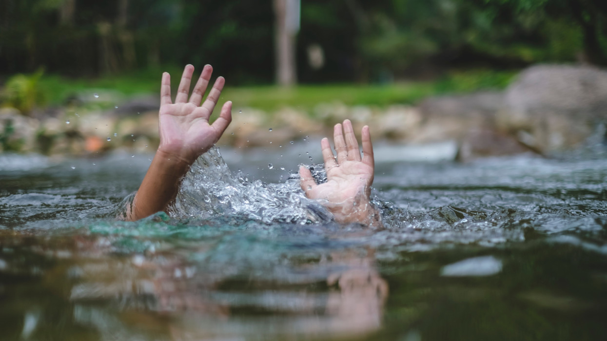 A folyóba fulladt ember segítségért nyúl. Vízbe fulladó gyermek keze kilóg a vízből.