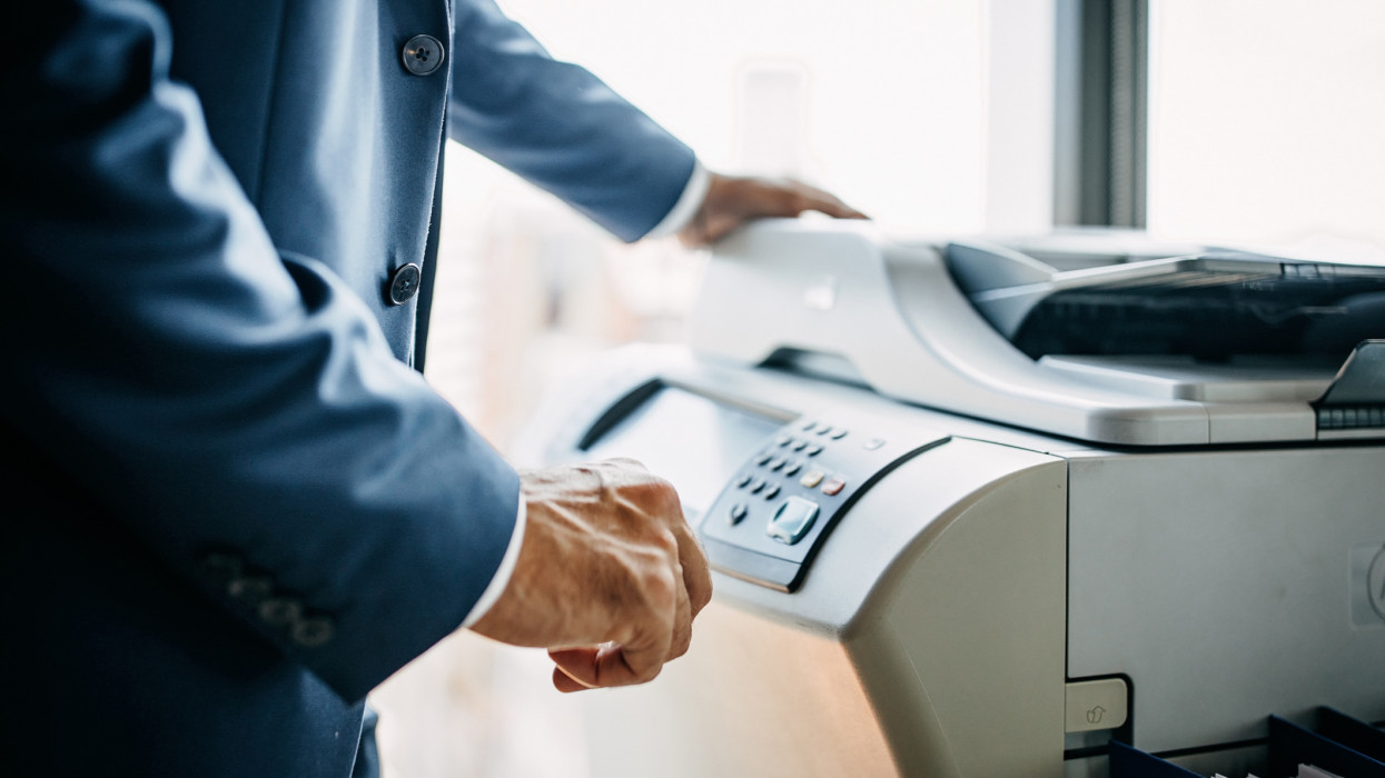 Midsection of businessman using photocopy machine at office