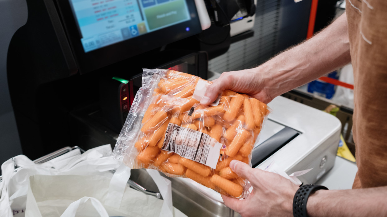 Close-up of unrecognizable white man purchasing groceries at self-checkout kiosk in supermarket