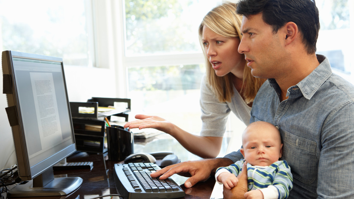 Couple working in home office with baby looking confused at the screen