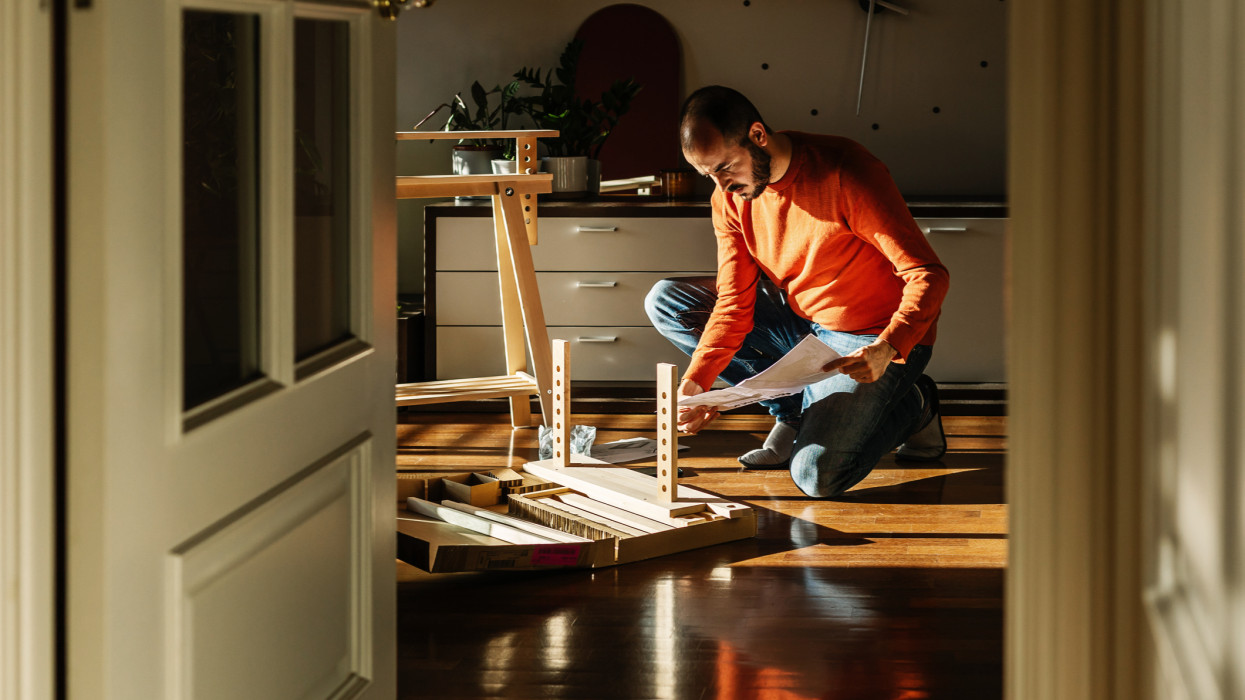 Young adult man assembling new trestle furniture in the morning at home