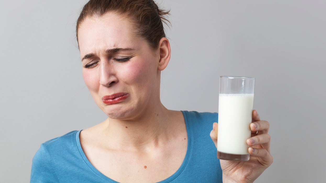 nauseous young woman disgusted at the idea of drinking a glass of smelly milk or white beverage, long header with copy space