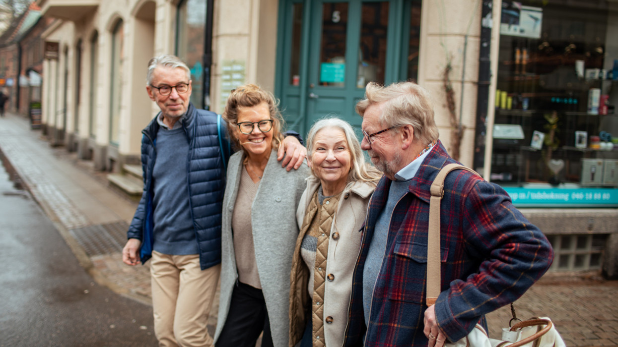 Close up of a small group of senior friends walking on a street downtown