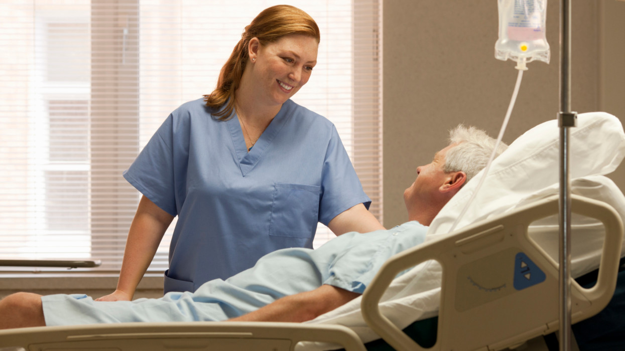 Smiling 30s woman nurse comforting male patient in hospital room