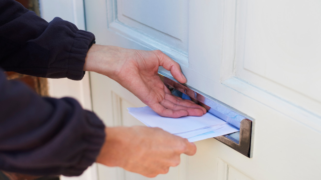 Close up of postman delivering post through residents letterbox