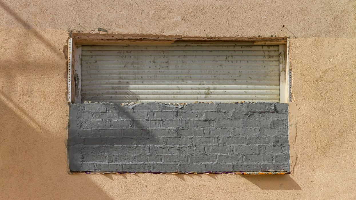 Madrid, Spain - May 21, 2022: Half boarded up window with blind