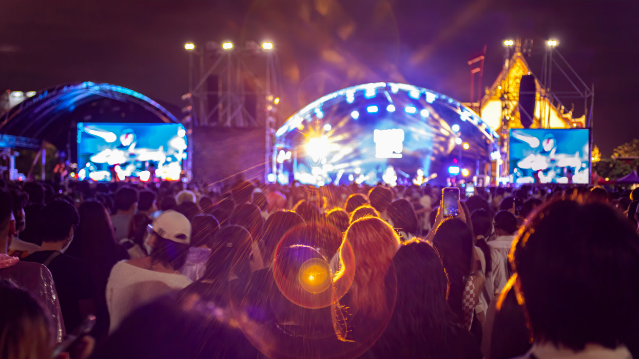 People at Music Festival with Illuminated Lights At Night Backgroun