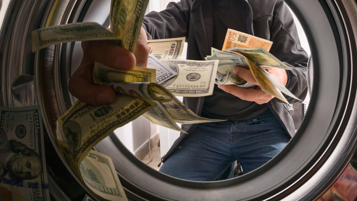 One caucasian male throwing money into a washing machine