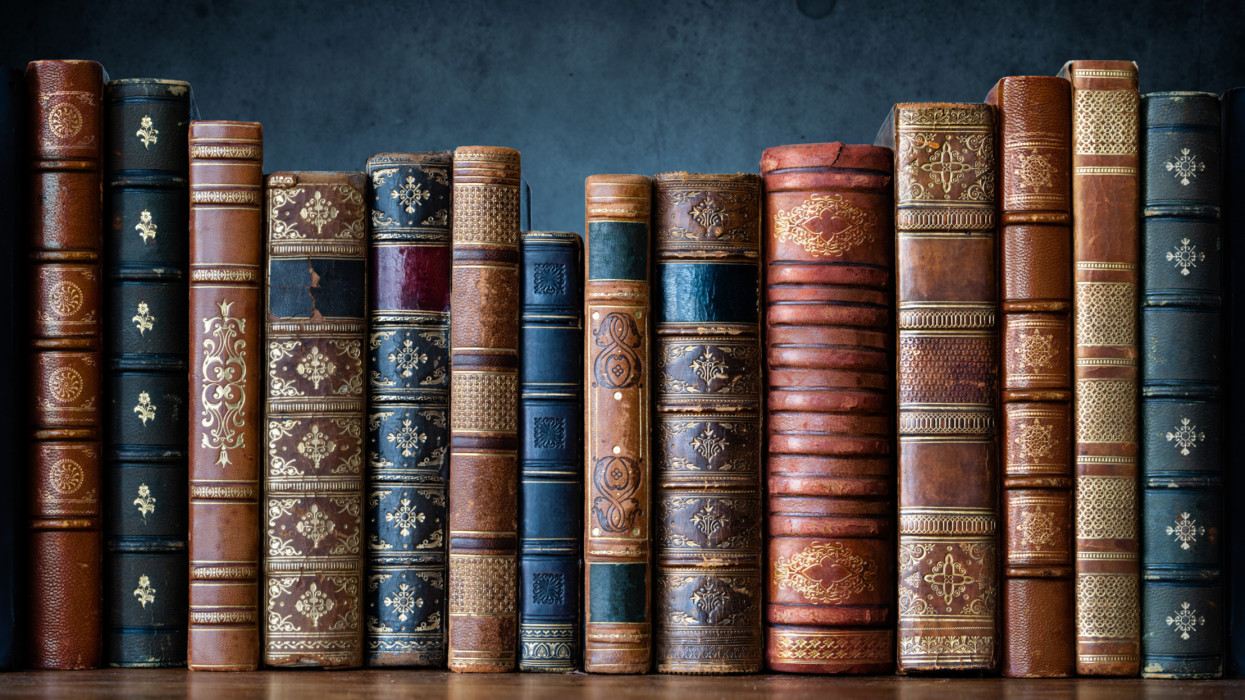 Old books on wooden shelf. Tiled Bookshelf background.  Concept on the theme of history, nostalgia, old age. Retro style. The book is a symbol of knowledge.