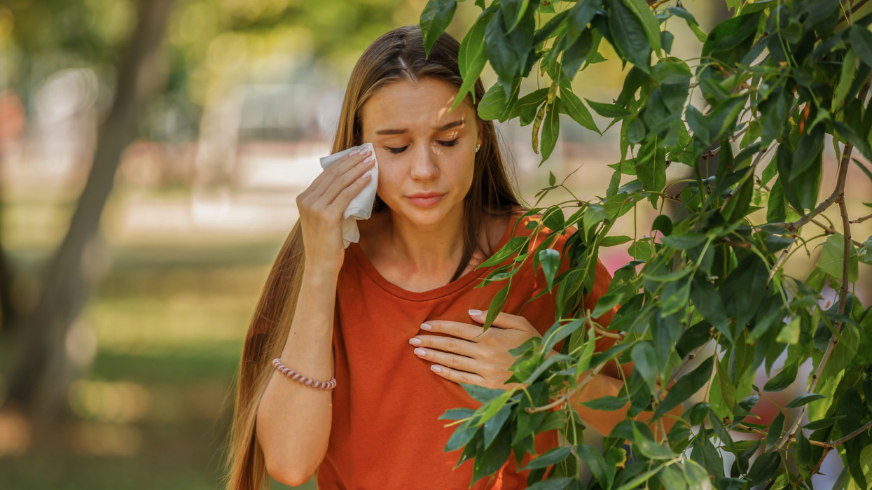 Beautiful Woman with Sight or Allergy Problems is Rubbing her Eyes with Paper Tissue During the Walk in a City Park on Sunny Day.