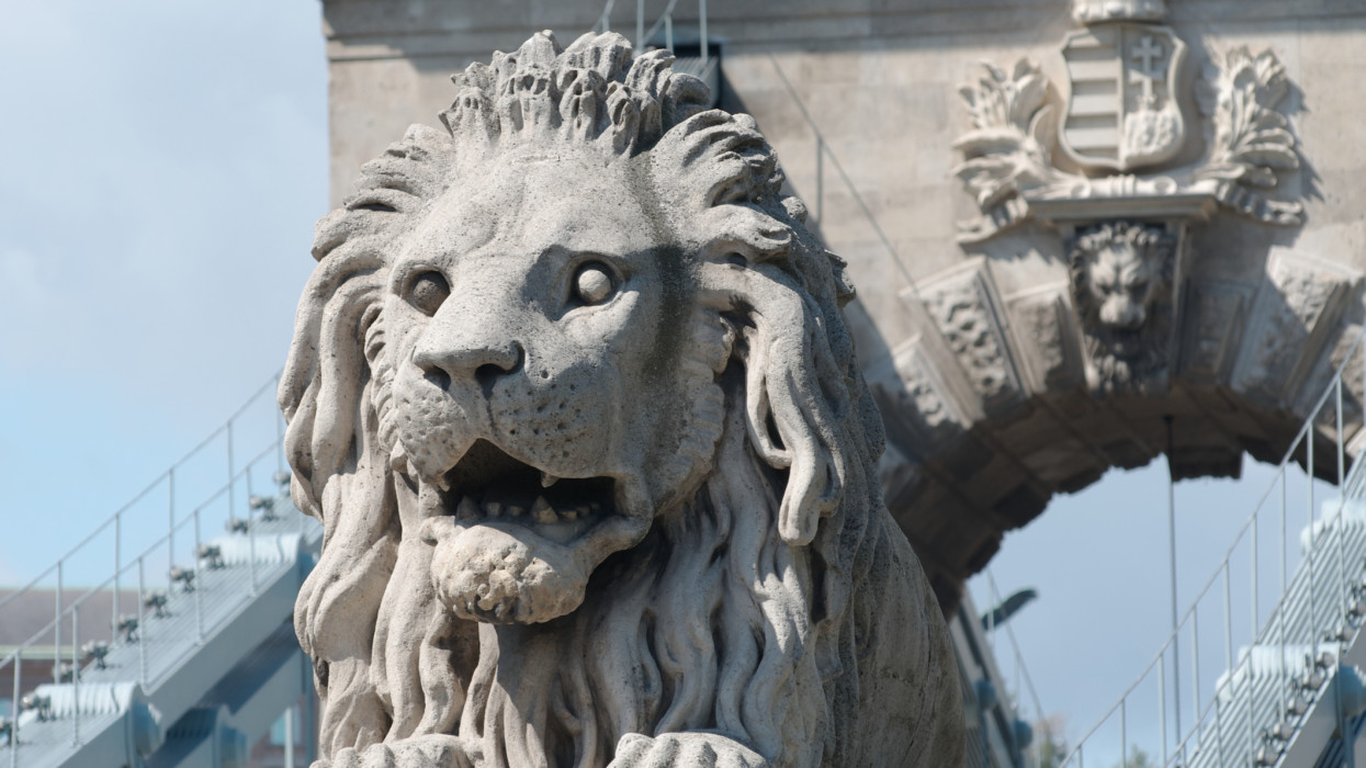 Carved stone lion guarding the approach to the Chain Bridge across the River Danube in Budapest, Hungary