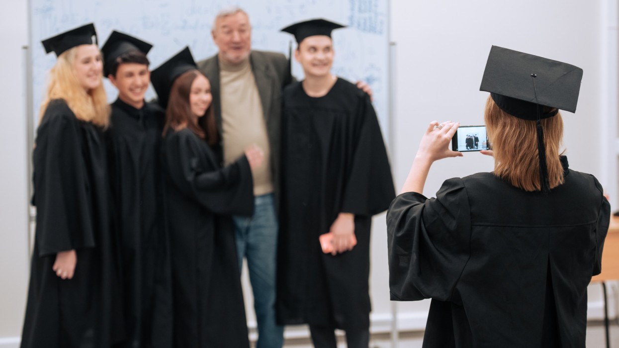 At the university, during the presentation of graduation diplomas, students in beautiful robes and hats are photographed with their dean of the faculty.