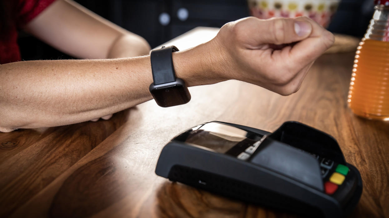 A customer woman making wireless or contactless payment using smartwatch in restaurant