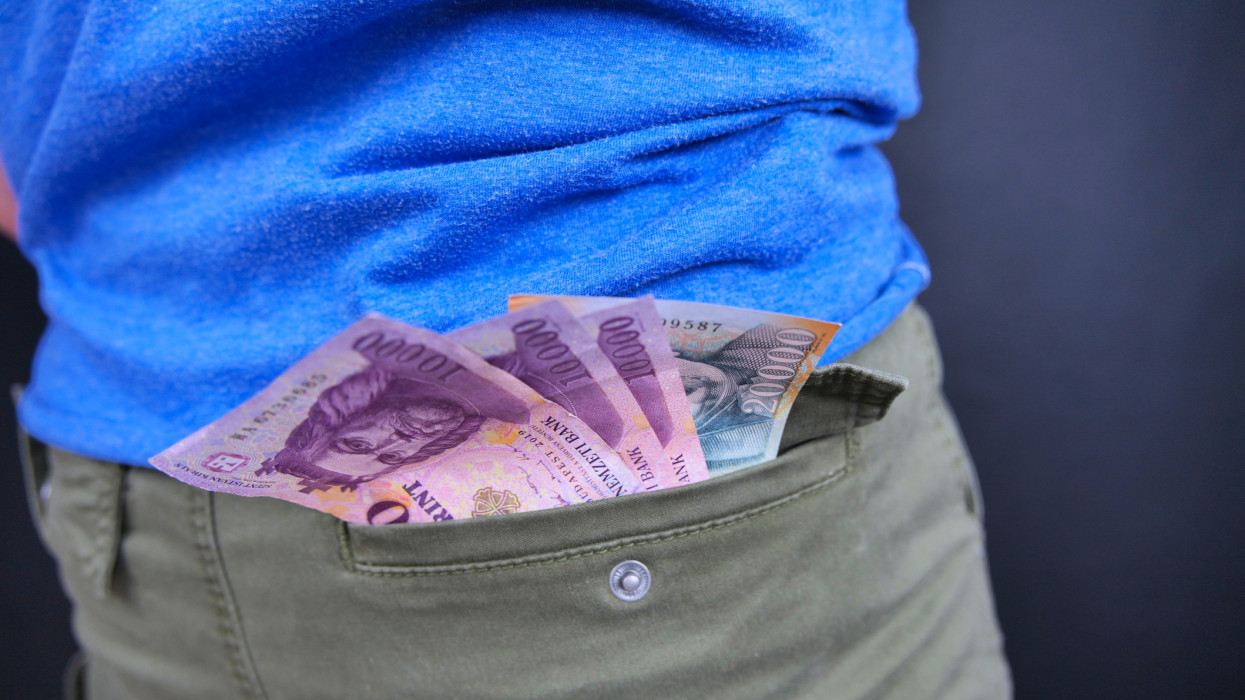 On the picture there are Hungarian forint banknotes in the pocket of a man. Three ten thousand forint banknotes and one twenty thousand forint banknote. Altogether 50000 HUF. The background is black. This picture is color saturation enhanced.