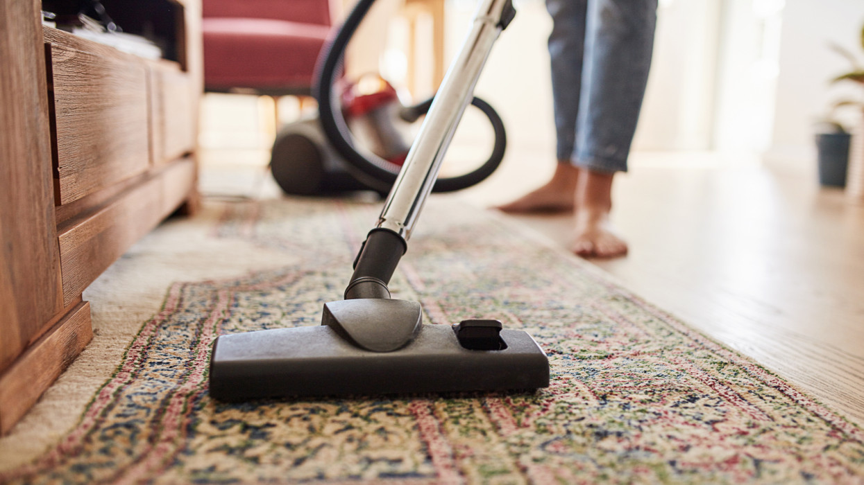 Shot of a young woman vacuuming the living room at home