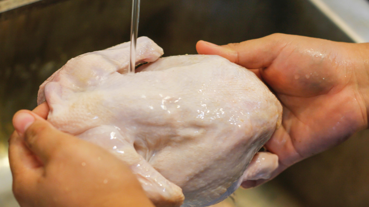 Close up Asian woman washing raw chicken before cooking at home, during Coronavirus lockdown