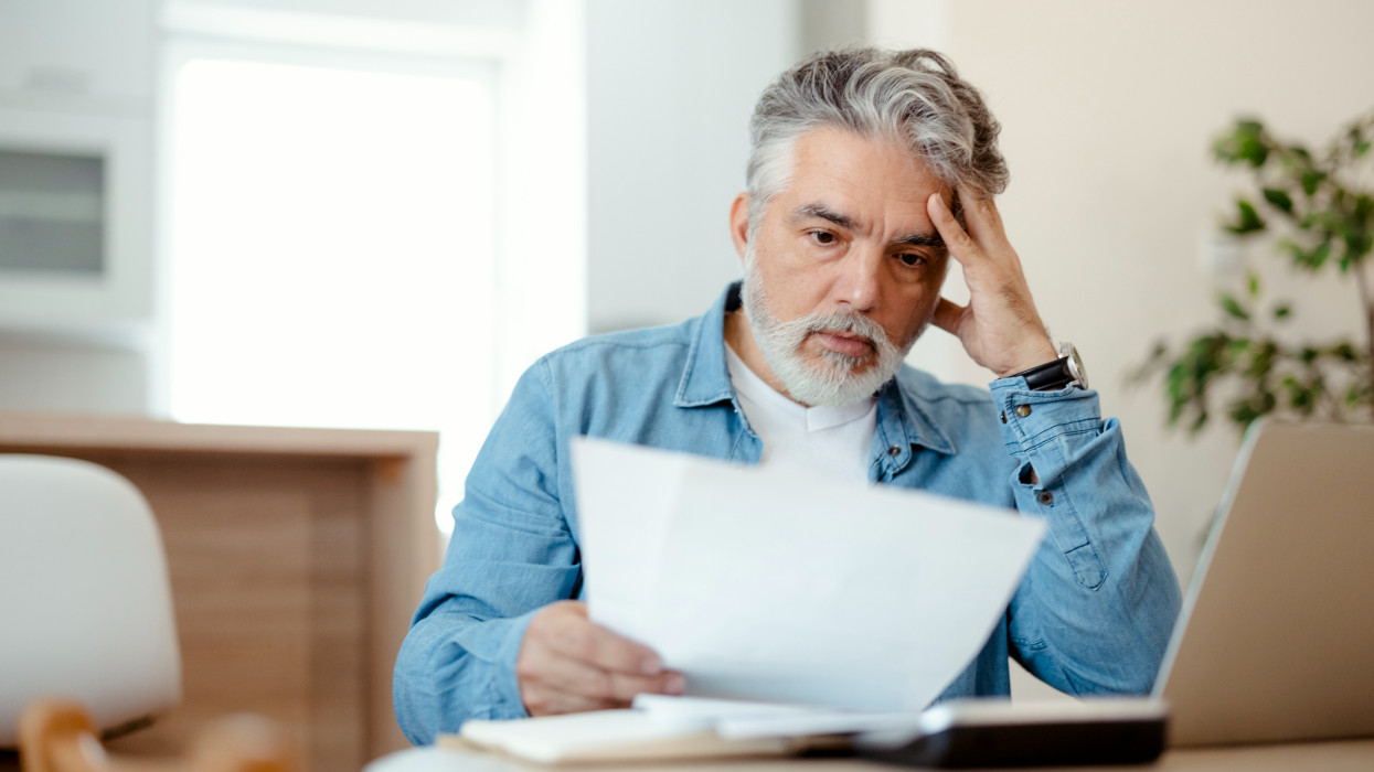 Worried middle-aged man confused and astonished by unbelievable news: high bill tax invoice, debt notification, bad financial report, money problem