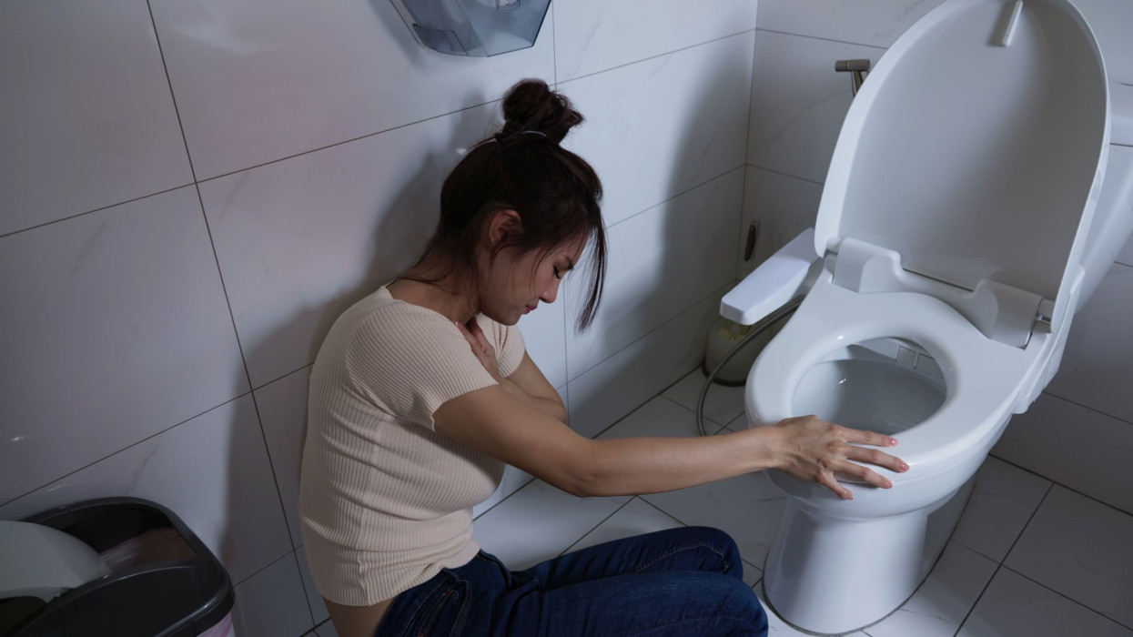asian woman feel pain touching toilet ready for vomit because sick or pregnancy sitting on floor in bathroom