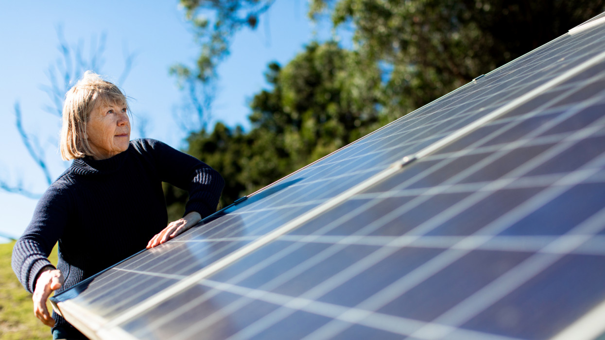 Senior female Aussie farmer manually checks the angle of her solar panels