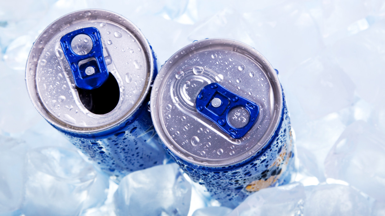 Photo of the top two chilled cans of energy drink in ice.