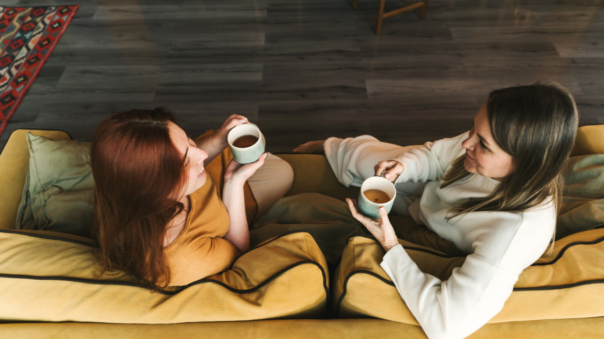 Two women are sitting and talking. Woman psychologist practicing with  patient women. Coach session between girlfriends. Therapists gestures. Female talking and drinking a cup of tea