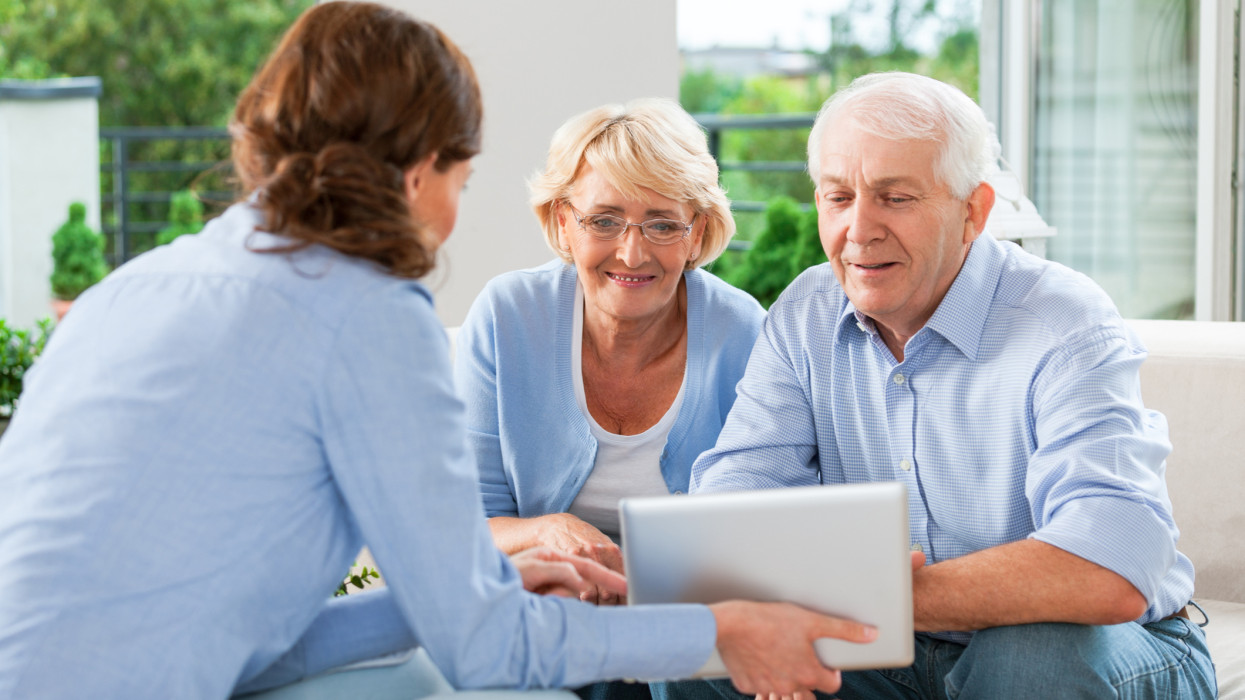 Senior couple having meeting with financial advisor or insurance agent at home.
