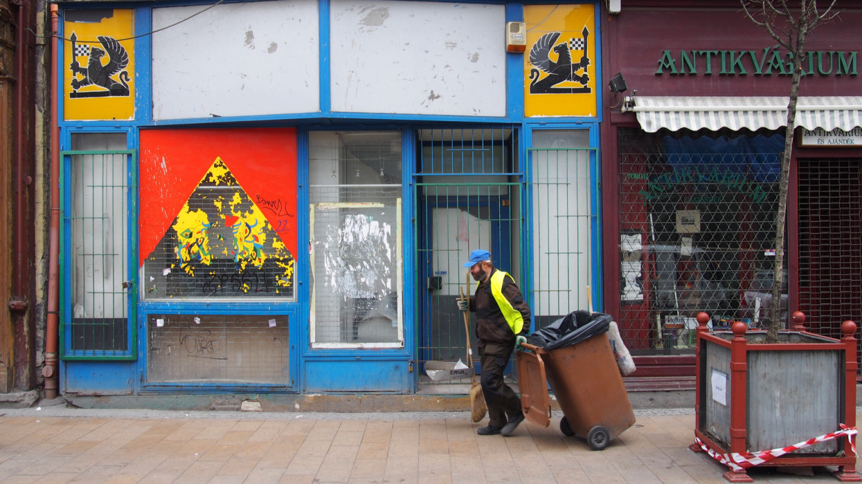 Budapest, Hungary - August 14, 2017: a street cleaner working outside an abandoned shop in Budapest closed