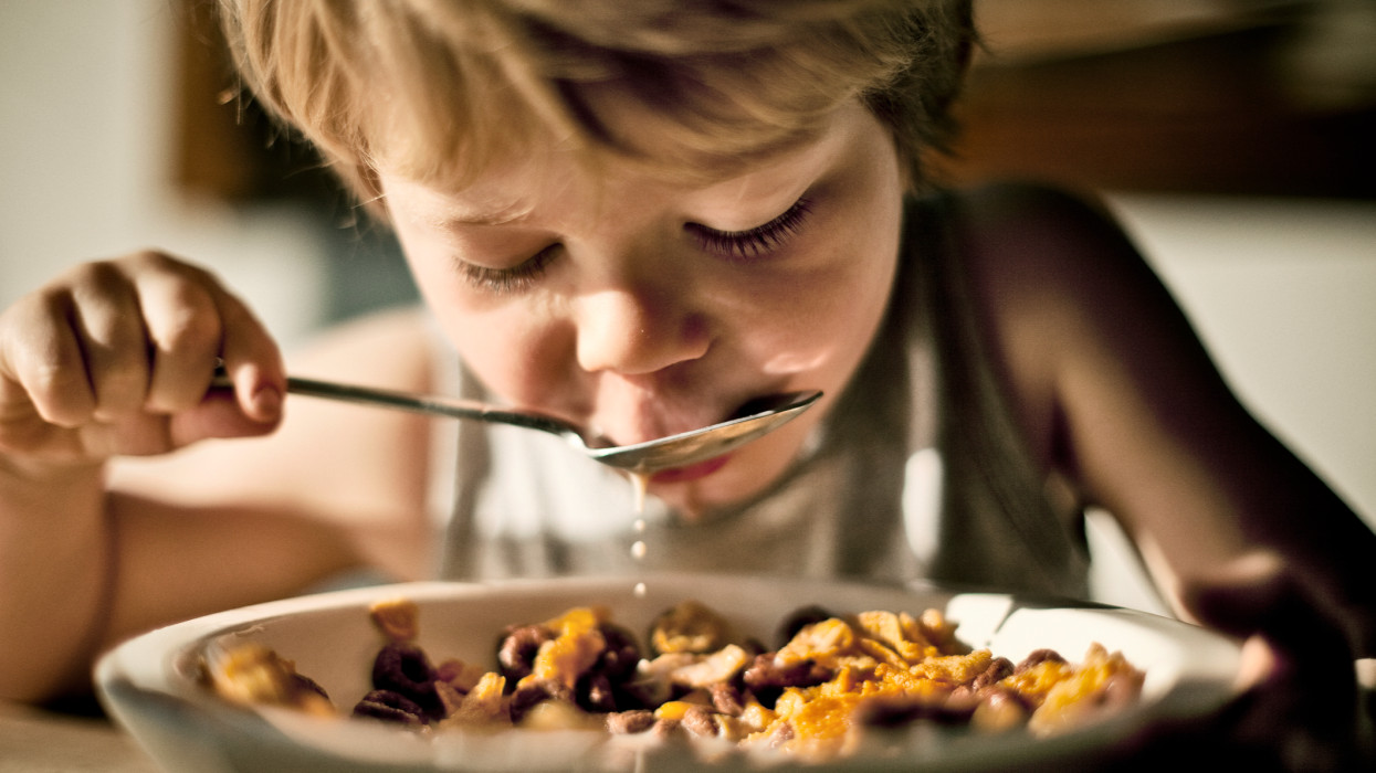 child eating bowl of cereal and milk dripping off spoon